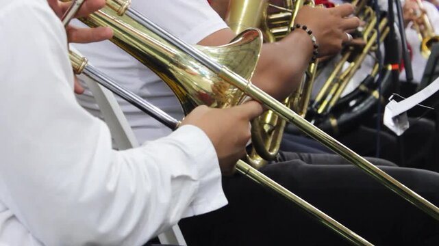 An unrecognizable young man sits while playing a trombone at a concert in Neiva, Huila, Colombia. Classical music concept