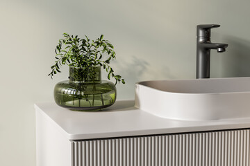 Minimalist bathroom detail with modern sink, black faucet, and green glass vase. Japandi-inspired...