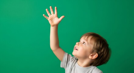 Happy child reaching up on green screen. Boy raising hand for chromakey background. Kid looking up with an open palm.