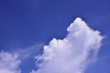 Obraz premium Large cumulus white cloud rising in a vibrant deep blue sky, creating a dramatic and peaceful atmosphere. A natural tropical sky scene from Bangladesh