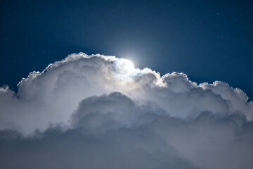 Sunlight breaking through a large cumulus cloud formation in a deep blue sky