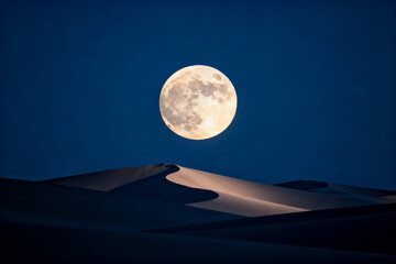 Full moon rising over sand dunes in a desert landscape at night