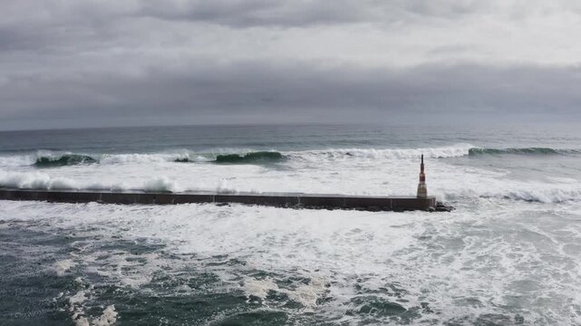 Huge waves crashing over Breakwater during winter storm Atlantic waves washing the lighthouse on Praia da Aguda sandy beach at Aguda settlement near Porto, Portugal. Incredible 4K flying drone video.