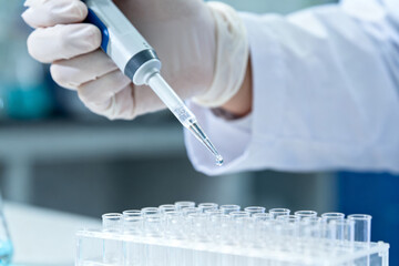Scientist using pipette to transfer liquid into test tubes in laboratory setting