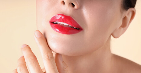 Woman with beautiful red lipstick on her lips against beige background, macro view