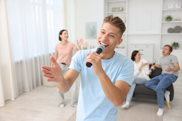 Fototapeta premium Young woman singing karaoke with friends at home, selective focus