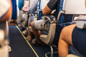 Travelers are sitting in an airplane cabin, focused on their surroundings. The image captures diverse clothing styles and relaxed body language as the flight progresses © Creative_Bird
