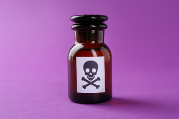 Bottle of poison with warning sign on purple background, closeup