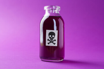 Bottle of poison with warning sign on purple background, closeup
