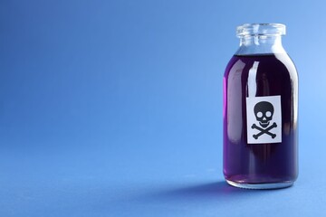 Bottle of poison with warning sign on light blue background, closeup. Space for text