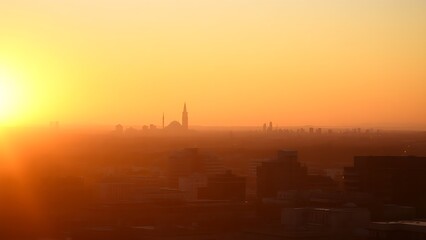 Fototapeta premium A serene sunset cityscape with golden hues, featuring distant urban silhouettes and a soft gradient sky.