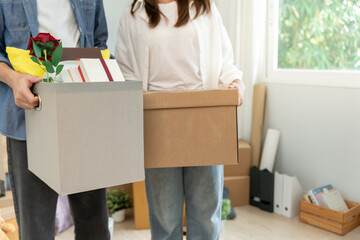 Moving house, relocation. Couples hold carton box contain equipment for new condominium, inside the...