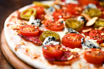 Pizza with salami, jalapeno pepper, cherry tomatoes and mozzarella cheese. Soft focus.	