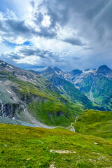 Fototapeta premium Majestic mountain landscape showcasing lush green valleys and dramatic peaks under a cloudy sky during a serene afternoon