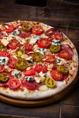 Pizza with salami, jalapeno pepper, cherry tomatoes and mozzarella cheese. Soft focus.	
