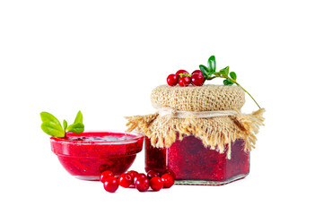 Jar and bowl of lingonberry jam with berries and leaves isolated on white background.