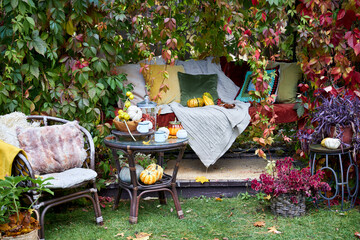 Cozy autumn still life in a garden with rustic table, pumpkins, quinces, glass jar, and warm seasonal decor. Outdoor fall atmosphere with natural colors, homely comfort, and countryside charm, perfect