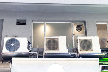 Structure of old air conditioner compressor source heat pumps and electrical circuit board on wall white on of building by glass window. Cooling pump technology for home or office industrial plant.