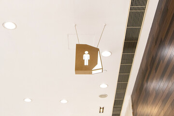 Sign brown lamp paper or plastic modern people man public toilet or bathroom sign light bulb LED hanging from ceiling with dim lights is background. Symbol notifying people with person men icon.