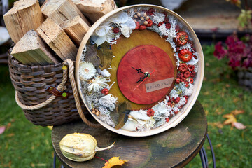 Handmade autumn wall clock decorated with dried flowers, moss and mini pumpkins. Rustic seasonal home decor with inscription Hello Fall, perfect for cozy fall interior or gift.