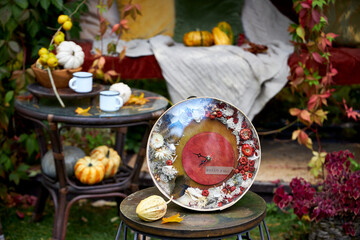 Handmade autumn wall clock decorated with dried flowers, moss and mini pumpkins. Rustic seasonal home decor with inscription Hello Fall, perfect for cozy fall interior or gift.