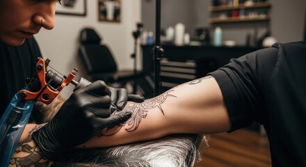 Man tattoo artist making tattoo on hand in salon. Professional tattooist at work on body art. Tattoo culture concept.