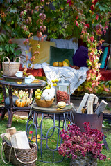 Cozy autumn still life in a garden with rustic table, pumpkins, quinces, glass jar, and warm seasonal decor. Outdoor fall atmosphere with natural colors, homely comfort, and countryside charm, perfect