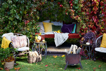 Cozy autumn terrace with rustic decor, wicker chairs, colorful pillows, firewood basket, and seasonal pumpkins. Decorative plants and vibrant fall foliage create a warm, inviting outdoor retreat, perf