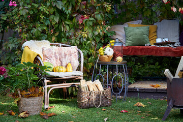 Cozy autumn terrace with rustic decor, wicker chairs, colorful pillows, firewood basket, and seasonal pumpkins. Decorative plants and vibrant fall foliage create a warm, inviting outdoor retreat, perf
