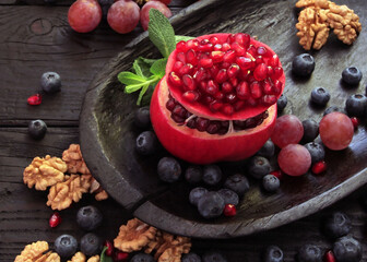 A beautiful ripe pomegranate on a dark wooden table. A variety of conceptual photos of pomegranates. Variable ideas for creating a look.