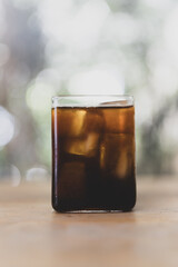Iced black coffee or americano in square shape glass on wood table
