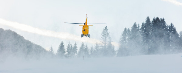 Scenic back view modern yellow rescue emergency mountain helicopter landing at forest ski slope at Alps mountain resort. Aviation transport machine silhouette alpine tourism service team © Kirill Gorlov