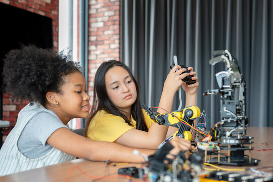 Diverse Young Girls Collaborating on a Robotics Engineering Project, Students Focusing on Building and Programming a Robotic Arm in STEM Class, Children Learning Hands-on Technology and Innovation - Powered by Adobe