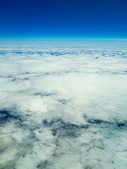 Above the clouds, a serene canvas of white and blue stretches endlessly under a clear sky