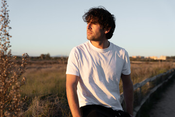 Man relaxing outdoor in golden afternoon sunlight, enjoying nature and contemplating during autumn sunset