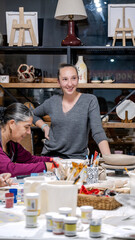 In an art studio a beautiful middle-aged woman artist is shaping clay at a table