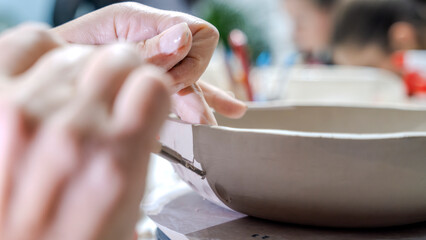 In an art studio a beautiful middle-aged woman artist is shaping clay at a table