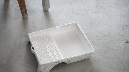 A white paint tub stands on a floor screed