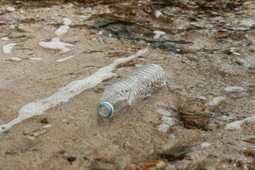 Obraz premium Plastic bottle on sandy beach pollution.