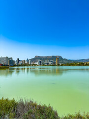 Obraz premium Sunshine over a tranquil lake with city skyline and mountains in the background on a clear day in summer