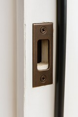 Closeup of Aged Bronze Residential Deadbolt Strike Plate on Door Frame with Weather Stripping
