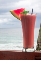 Refreshing Watermelon Smoothie by the Ocean with a Mint Garnish