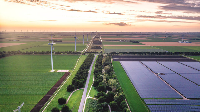 Drone view of rural evening landscape with wind and solar power plant in Netherlands. Green energy.