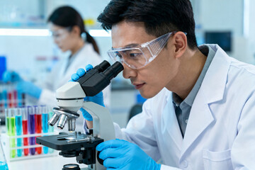 Scientist examining sample under microscope in laboratory setting