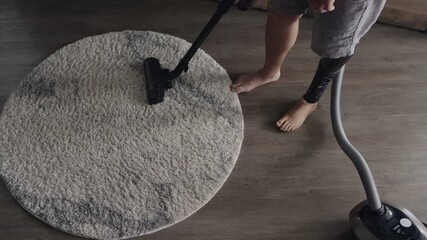 Overhead shot of an amputee vacuuming a living room carpet with a bionic leg, showcasing technology in everyday life.
