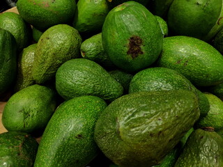Pile of fresh green avocados sitting in market display, ready for sale and consumption, showcasing the vibrant colors and textures of healthy food.