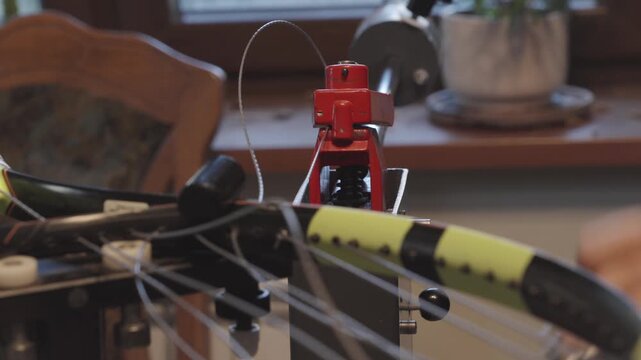 Manual stringing of a tennis racket on machine	