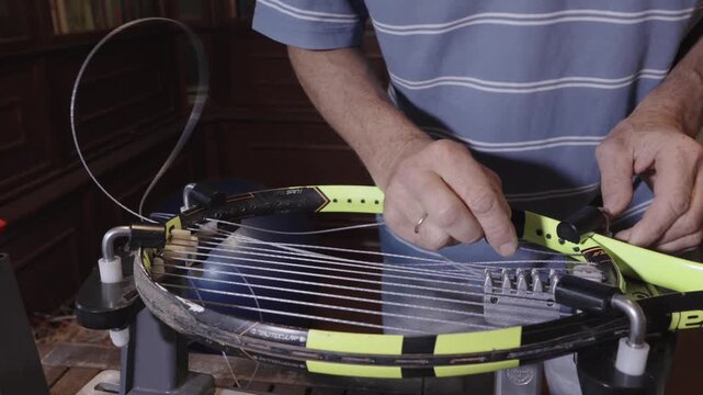Manual stringing of a tennis racket on machine	