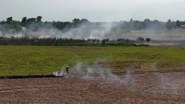 A series of drone clips showing farmers burning rice fields after harvest, creating thick smoke in the rural landscape of Vietnam. The footage captures this traditional practice.