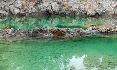 Scenic emerald pond with cliffs and reflection of trees.